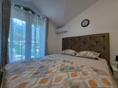 a bedroom with a bed with a clock on the wall at G apartment city centre Budva in Budva