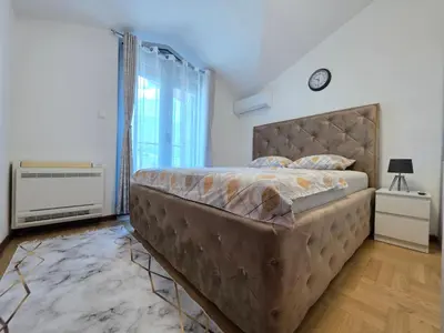 a bedroom with a large bed and a clock on the wall at G apartment city centre Budva in Budva