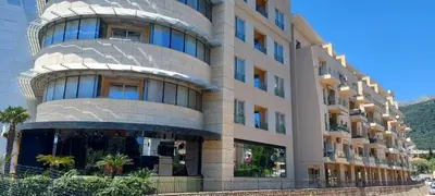 a building with a circular facade with palm trees in front at Seaside Milena Appartment in Budva