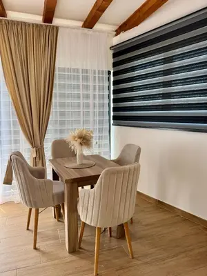 a dining room with a wooden table and chairs at Kangaroo Apartmani in Prijevor