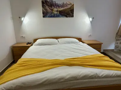 a bedroom with a bed with a yellow blanket on it at Kangaroo Apartmani in Prijevor