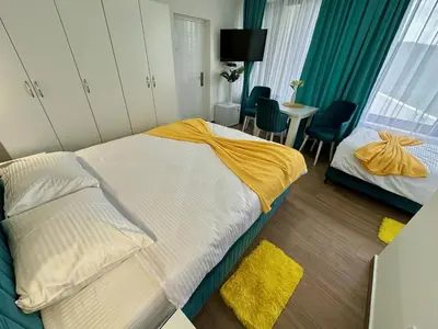 a bedroom with a bed with a yellow blanket on it at Kangaroo Apartmani in Prijevor