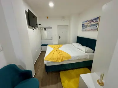 a small bedroom with a bed with a yellow blanket at Kangaroo Apartmani in Prijevor