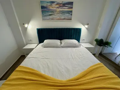 a bedroom with a large bed with a yellow blanket on it at Kangaroo Apartmani in Prijevor