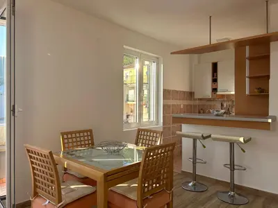 a dining room with a glass table and chairs at Green square apartment Budva in Budva