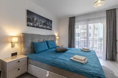 a bedroom with a blue bed with a large window at Jasmine 2-bedroom apartment in Becici
