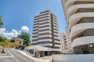 a tall apartment building in a parking lot at Twin Towers LT Luxury in Becici