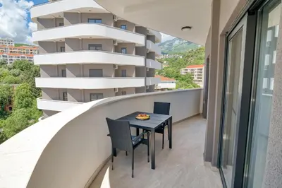 a balcony with a table and chairs in front of a building at Twin Towers LT Luxury in Becici