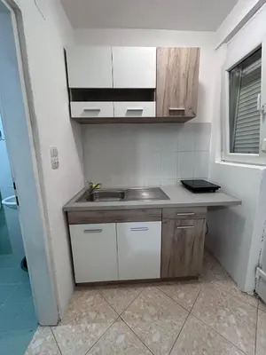 a small kitchen with a sink and white cabinets at Apartmani Čanj in Čanj