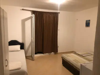 a room with two beds and a sliding glass door at Apartmani Čanj in Čanj