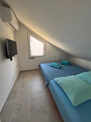 a small bedroom with a blue bed and a window at Little Stone House in Utjeha