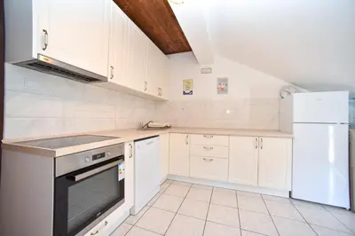 a kitchen with white cabinets and a stove and refrigerator at Apartmani Bonik in Budva