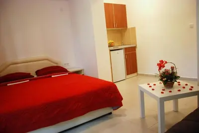 a bedroom with a red bed and a table at Apartmani Bonik in Budva