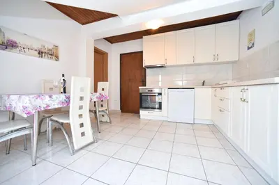a kitchen with white cabinets and a table and a counter at Apartmani Bonik in Budva