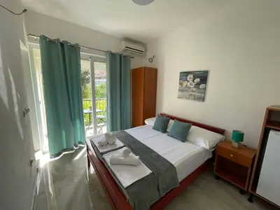 a bedroom with a bed with green curtains and a window at Elsa in Ulcinj