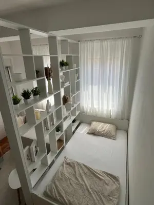 a small room with a bed and shelves at Studio Soleil in Cetinje