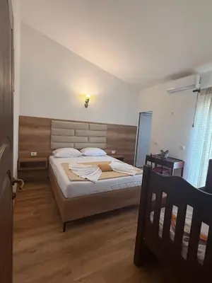 a bedroom with a large bed with a wooden headboard at Apartments George in Ulcinj