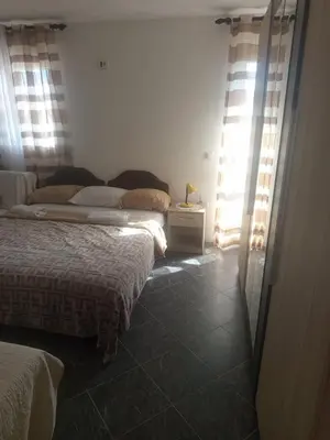 two beds in a bedroom with the sun shining through the windows at Apartman aleksej in Kućišta