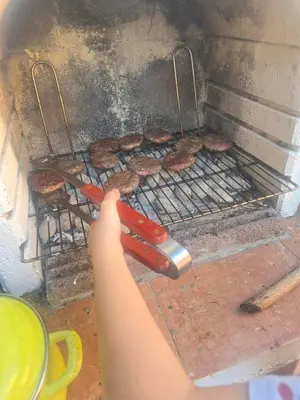 a person is cooking hamburgers on a grill at Sunny Lemon Garden in Petrovac na Moru