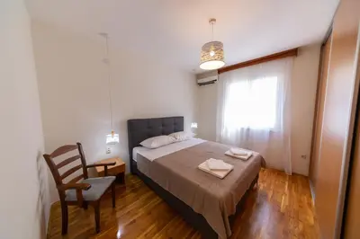 a bedroom with a bed and a chair and a window at KENOVA Apartment in Dobrota