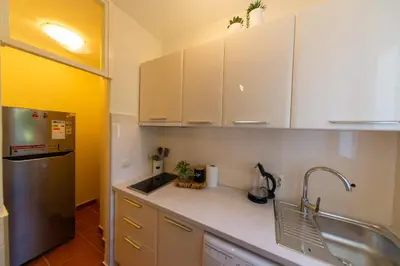 a kitchen with white cabinets and a sink and a refrigerator at KENOVA Apartment in Dobrota