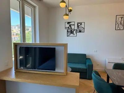 a living room with a flat screen tv and a blue couch at Skyline Premium Residences Becici in Becici
