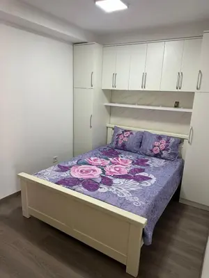 a bedroom with a bed with a purple comforter and white cabinets at Apartman Vuk in Budva