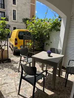 a table and chairs on a patio with a yellow car at Apartman Vuk in Budva