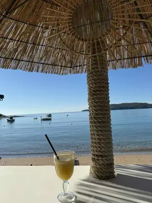 a drink sitting on a table next to a straw umbrella at Studio apartman Melissa in Budva