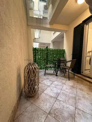 a patio with two tables and benches and a green wall at Studio apartman Melissa in Budva