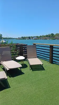 two chairs and a table on a deck with the water at Mimas HOUSE ADA BOJANA in Ulcinj
