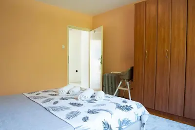 a bedroom with a bed with white sheets and a wooden cabinet at Central Apartment Dobrota II in Kotor