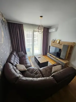 a living room with a leather couch and a television at Agape Bečići Apartment in Becici