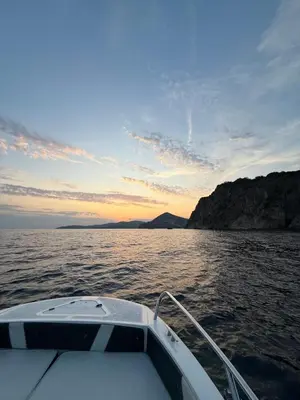 a boat in a body of water with a sunset at Apartman Dunja Bečići in Becici
