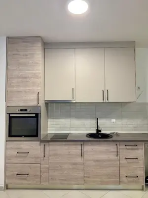 a kitchen with white cabinets and a sink at Apartman Dunja Bečići in Becici