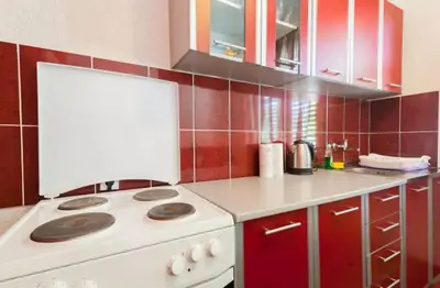 a kitchen with a white stove and red cabinets at Stefanelo in Ulcinj