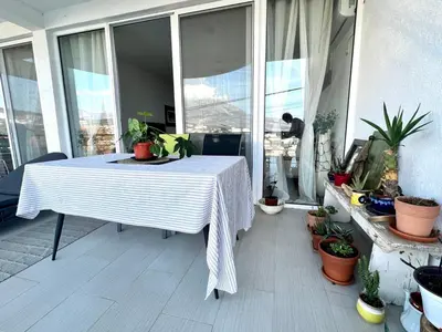 a table on a balcony with potted plants on it at Hladna Uvala Apartment - 2 bedroom in Bar