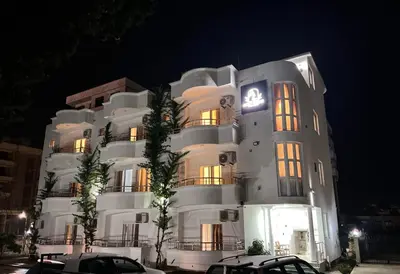 a large white building with cars parked in front of it at Addy's Apartments in Ulcinj