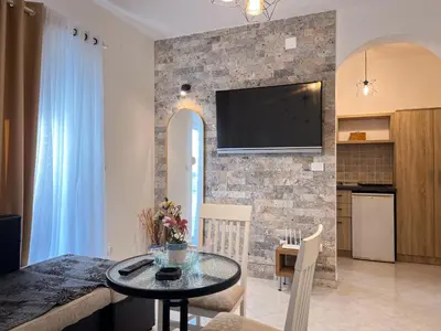a living room with a table and a tv on a brick wall at Addy's Apartments in Ulcinj