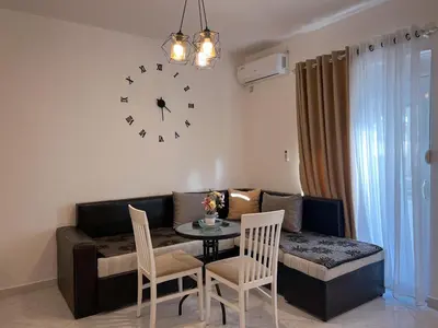a living room with a table and a clock on the wall at Addy's Apartments in Ulcinj