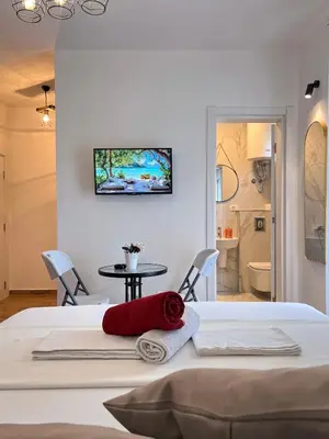 a bedroom with a bed and a table and a bathroom at Addy's Apartments in Ulcinj