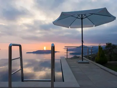 a white umbrella sitting next to a body of water at Villa Infinity swimming pool above Saint Stephan in Andriči°i