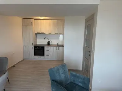 a living room with a blue chair and a kitchen at Casa Oliva Apartments in Katun