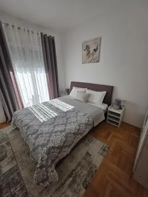 a bedroom with a bed with a blanket and a window at Dagana in Budva