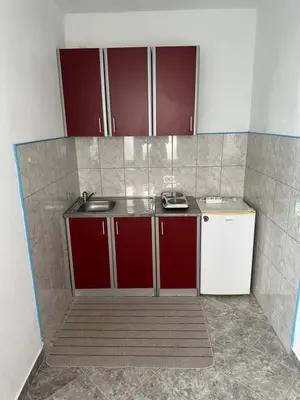 a small kitchen with red and white cabinets and a sink at Apartments Nera in Utjeha