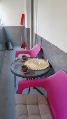 a table with two pink chairs and a table with food on it at Apartman Vuk 15 in Budva