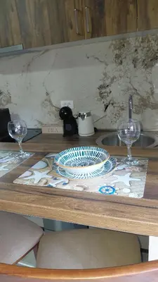a table with two wine glasses and plates on it at Apartman Vuk 15 in Budva