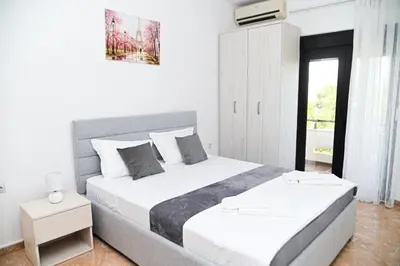 a white bedroom with a large bed and a window at Antonios Apartments in Ulcinj