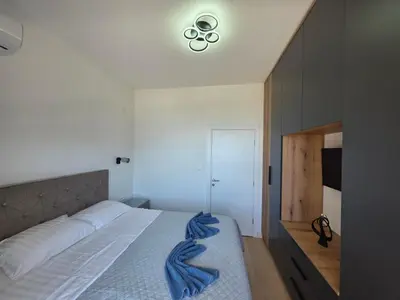 a bedroom with a large bed with a light on the ceiling at Azure Elite Apartment in Becici