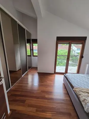 a bedroom with a bed and a wooden floor at Apartman Milunović in Dobrota